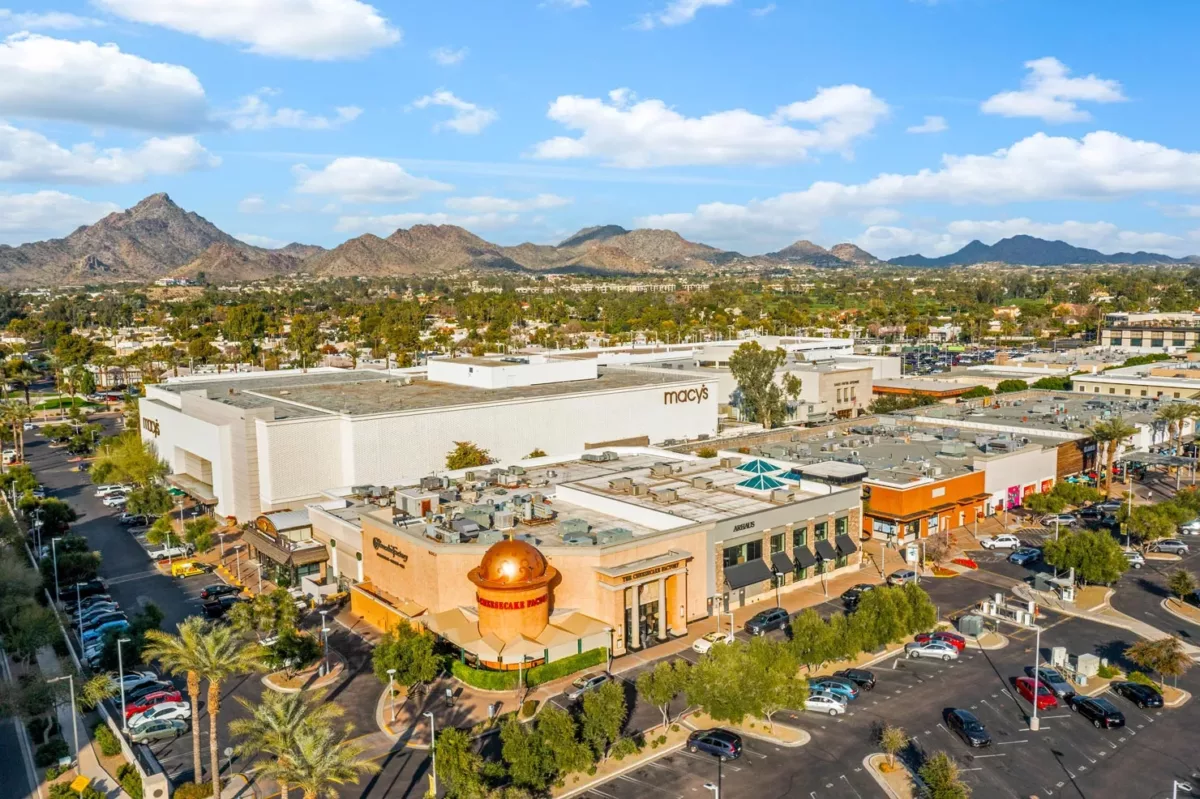 Aerial view of shopping center with Macy's, restaurants, and mountain backdrop.