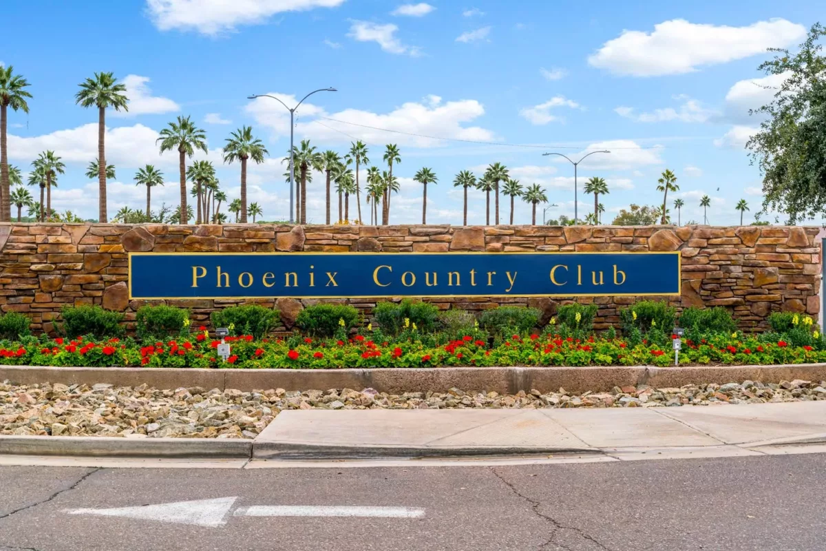 Phoenix Country Club entrance sign with palm trees and landscaped flowers.