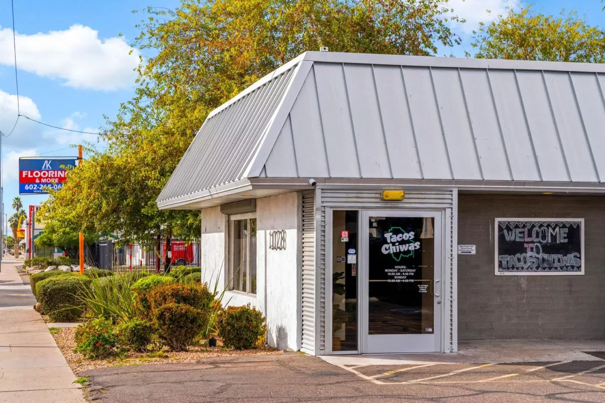 Tacos Chiwas storefront with gray roof, sidewalk entry, and desert landscaping.